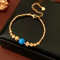 Vintage gold-tone beaded bracelet with a central blue bead on a black box - Bracelet / Gold-Blue