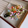 Close-up of a colorful flower cluster hair clip in a wooden jewelry display case - Green Multicolor