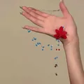 Detailansicht einer handgefertigten Perlenkette mit roter Stoffblume und blauen Perlen - Rote Stoffblume Stil