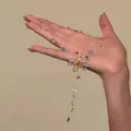 Gedetailleerd overzicht van een kleurrijke glasparel bloemketting vastgehouden. - Wit-Blauw-Groen-Bloem