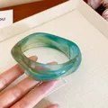 Detailed view of square marbled acrylic bracelet with green and blue striped swirls - Blue
