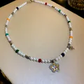 Nahaufnahme einer bunten Perlenkette mit glitzerndem Blumenanhänger und Herzanhängern. - Lachelnde Blume Herz-Anhänger Stil