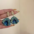 Elegant iridescent blue fan-shaped drop earrings featuring gold textured metal studs. - Fan Earrings
