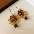 Macro view of vintage ethnic earrings featuring tiger eye stones and intricate zircon beadwork - Gold & Coffee & Champagne