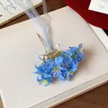 Primer plano de una horquilla de flores de tela azul con cintas fluidas elegantes - Azul