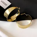 Primo piano di eleganti orecchini a cerchio dorati con trama spazzolata e perni in argento - Oro