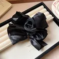 Close-up of a large black fabric bow hair claw clip with satin finish on a display tray. - Hair Claw No. 1 (1#) / Black