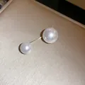 Primo piano di una spilla minimalista con doppia perla e barra dorata su fondo champagne - Doppia Perla Minimalista (5#)