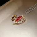 Close-up of a vintage rocking horse brooch with red enamel and clear rhinestones - Red