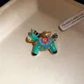 Close-up of a vintage enamel horse brooch with colorful patterns and gold-tone details - Green Flower