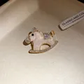 Close-up of elegant pink enamel rocking horse brooch with sparkling rhinestones - Pink