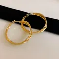 Detailed view of elegant gold twisted hoop earrings showing refined metal texture - Gold