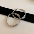Close-up detail of silver geometric twisted hoop earrings with multi-layer texture design - Silver