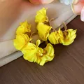 Detail shot of vibrant yellow chiffon flower hoop earrings with high-end texture. - Silver Earring Post Style / Gold-Yellow