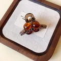 Macro detail of amber acrylic mini hair claw clip with round beads on decorative wood tray - Mini Round Style / Brown