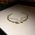 Close-up of elegant double-layer gold cuff bracelet with sparkling pink butterfly - Gold