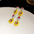 Detail von geometrischen Ohrhängern mit gelber Emaille und pinkfarbenen Kristallen - Silber-Ohrstecker - Gold - Bunt