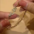 Close-up detail of a stylish gold horseshoe buckle chain bracelet held by elegant hands. - Gold
