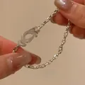 Detail view of a silver-tone chain bracelet with horseshoe buckle design held by hands. - Silver