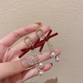 Gros plan de boucles d'oreilles nœud en velours rouge avec glands en strass et perles. - Style Gland Vintage (27#)