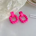 Gros plan de boucles d'oreilles carrées torsadées rose vif avec un fini mat moderne - Style Carré Dépoli (35#)
