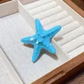 Detail shot of a vibrant blue acrylic starfish hair clip resting in a wooden jewelry box. - Duckbill Hair Clips / Blue