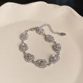 Detailansicht einer Vintage-Halskette mit Kristalltropfen auf einem cremefarbenen Keramikteller - Einzelnes Armband / Silber