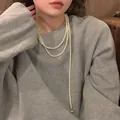 Detailed view of an elegant multi-layer pearl necklace worn on a casual grey sweatshirt. - Long Pearl Heart Style (13#)