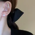 Close-up of an elegant pearl stud earring on model's ear with black bow - Silver Pin - White 8mm