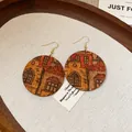 Close-up of vintage wooden earrings with printed architectural patterns in a rustic tray - House Style / Coffee