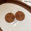 Detailed macro view of vintage mandala pattern print on round wooden earrings - Floral Round Style / Coffee