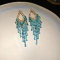 Detailed view of heavy-duty rhombus earrings featuring shimmering blue zircon tassels. - Silver Earring Post - Gold - Blue
