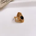 Detailed view of gold-plated hollow flower ring with a black oval zircon stone. - 24# Ring - Gold - Black