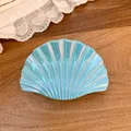 Detail of an iridescent light blue shell-shaped hair claw clip on wood surface - Large Shell Claw Clip / Large / Blue