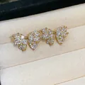 Macro detail of gold-plated bow stud earrings with sparkling cubic zirconia - Gold