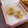 Macro view of vintage gold rose earrings with yellow gems and pearls in pink box - Gold