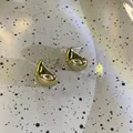 Gros plan détaillé de boucles d'oreilles en métal doré en forme de C avec fini miroir - Style Brillant / Or
