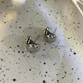 Vue rapprochée de boucles d'oreilles clous en métal en forme de C, fini argent brillant - Style Brillant / Argent