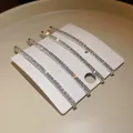 Vista dettagliata di quattro eleganti fermagli per capelli con strass argento su cartoncino. - Stile 3 / Confezione da 5 / Argento