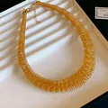 Detailansicht des markanten, goldfarbenen Feder-Halsreifs in einer Schmuckschatulle. - Großer Federstil / Gold