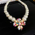 Detailed view of pearl necklace with a colorful rhinestone flower pendant on black background - White