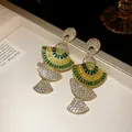 Close-up detail of vintage fan-shaped earrings encrusted with green and clear crystals - Earrings Only / Green