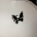 Macro view of elegant silver-tone butterfly jewelry with black enamel on a white plate - Butterfly Ring Gold