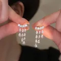 Detailed macro shot of sparkling zircon teardrop tassel ear cuffs with 18k gold plating - Clip-on (HE31130) / Silver