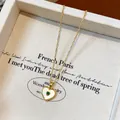 Detail view of a gold-plated heart necklace with mother of pearl and green gemstone - Heart / Gold