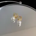 Detailansicht eleganter vergoldeter Perlenohrringe, die sich im Spiegel spiegeln - Silbernadel Gold