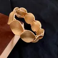 Nahaufnahme eines goldfarbenen Metallarmbands mit gehämmerter Textur und mattem Finish. - Gehämmertes Kreis-Stil (WB089) / Gold