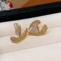 Detail view of exquisite 18k gold plated leaf stud earrings set with zircon stones - Gold