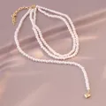 Elegante französische zweilagige Perlenkette mit einem zarten goldenen Herzanhänger - Doppellagige Perlenkette mit Herz-Metallanhänger