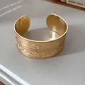 Nahaufnahme antiker Prägemuster auf einem breiten goldenen offenen Metallarmreif - Umweltfreundliches Material (HB4426) / Gold
